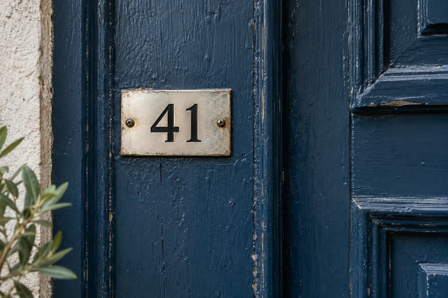Metal address plate reading 41 on a navy-painted wooden door