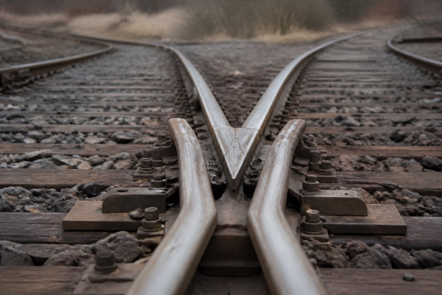 Two railway rails converging at a set of points on a quiet stretch of track