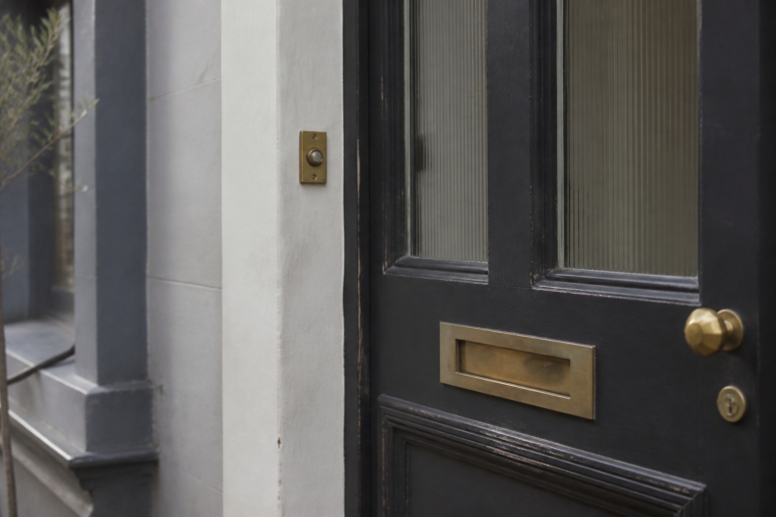 A front door with a brass bell push beside it and a letterbox in the panel below