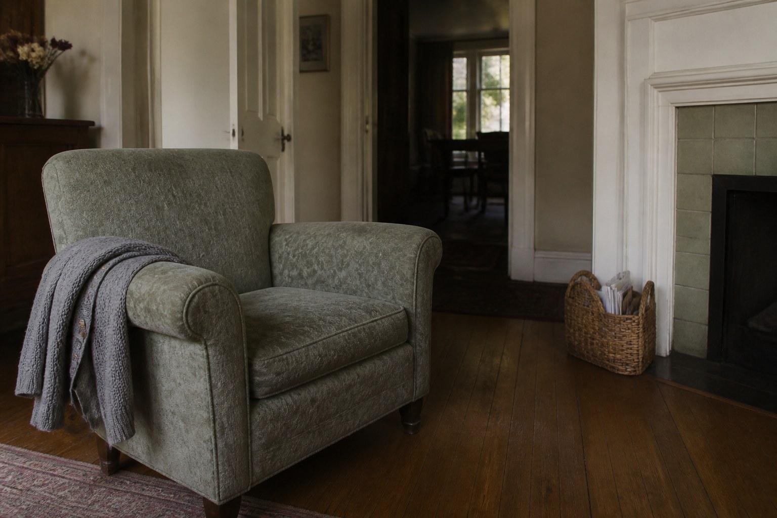 A folded cardigan over the arm of an empty armchair in a quiet room