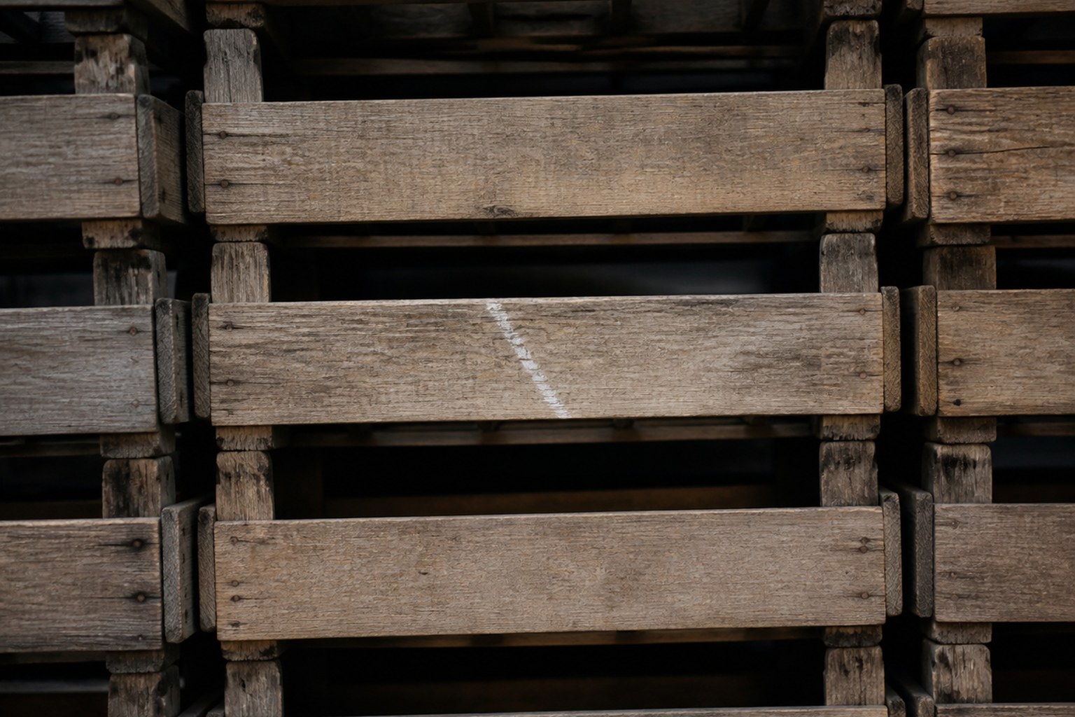 A stack of identical wooden crates with a chalk mark on one