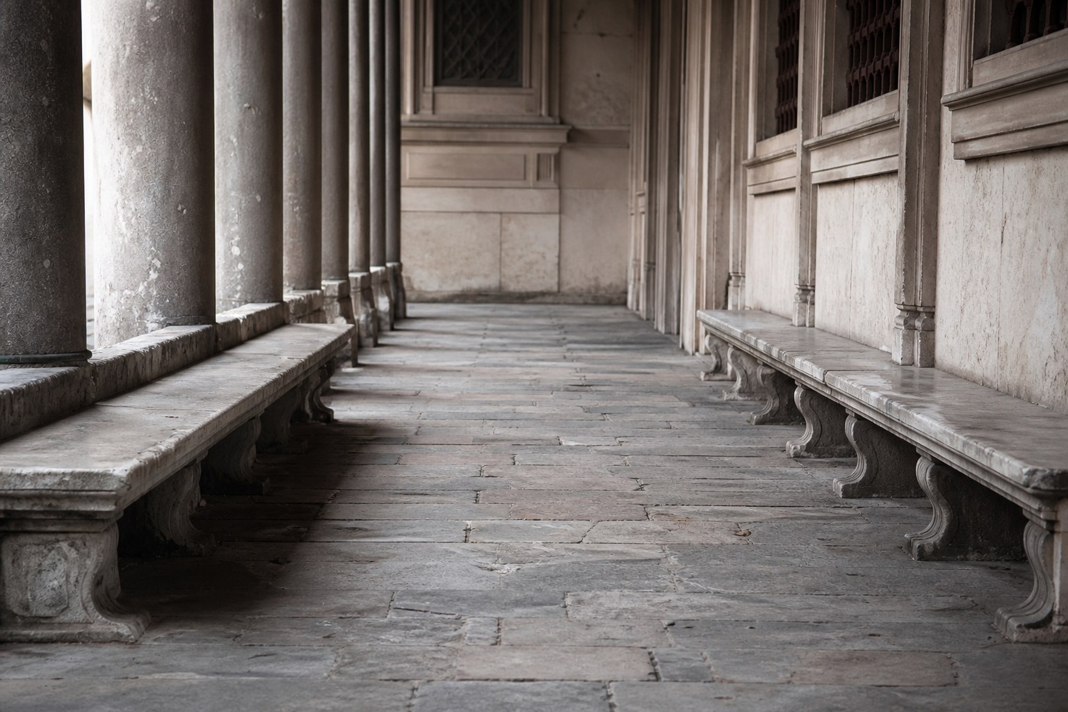 Stone benches facing each other under a colonnade, all empty