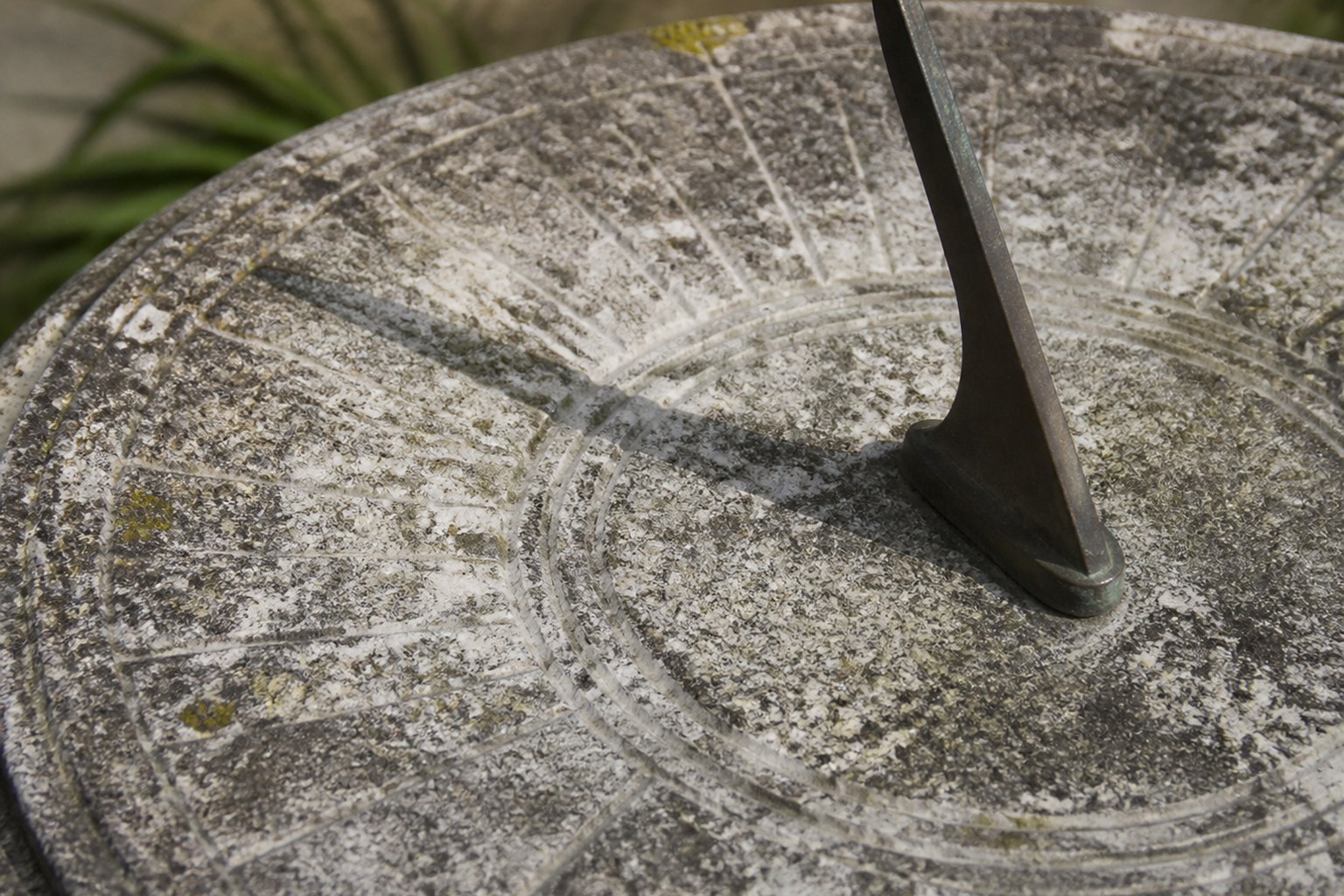 A weathered garden sundial with its gnomon casting a short shadow