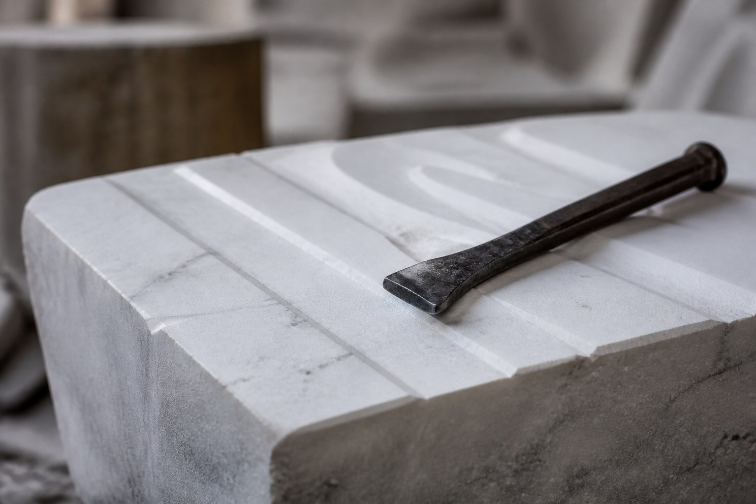 A marble block with shallow chiselled guide channels and an iron chisel resting on it