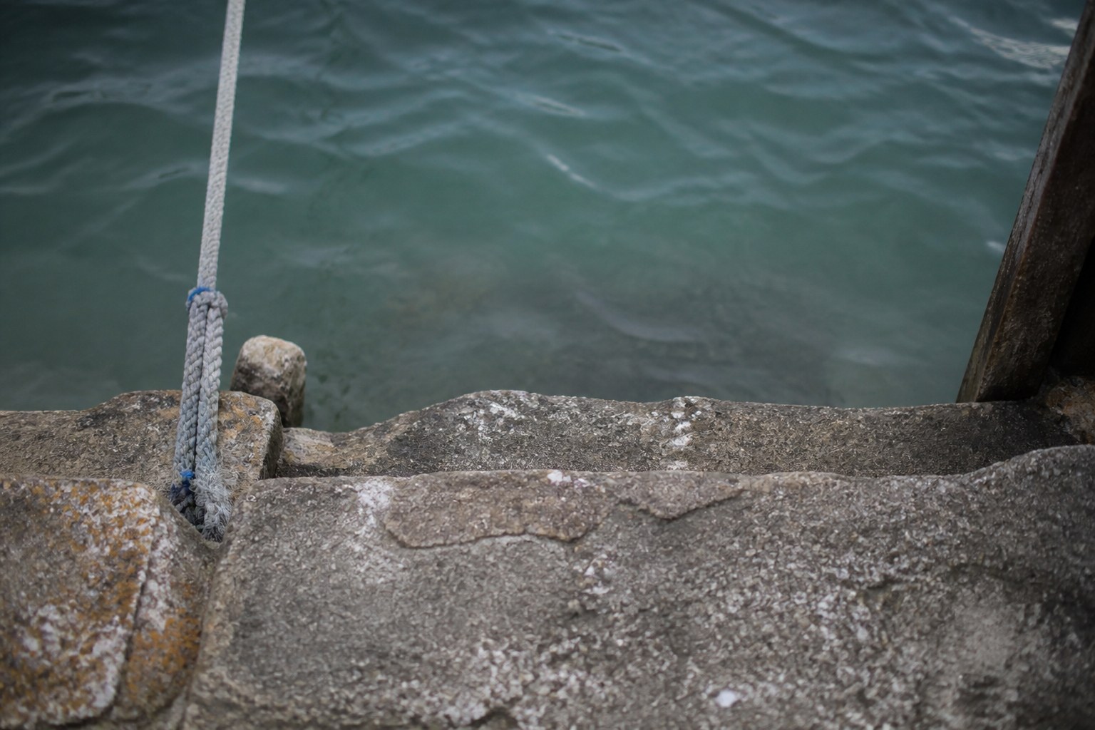 A worn stone step at a harbour edge where a gangway would land