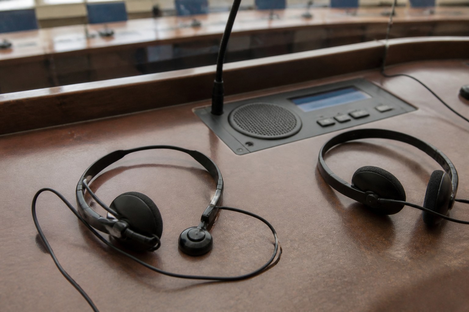 Two interpreter headsets on a bare conference desk beside a small console