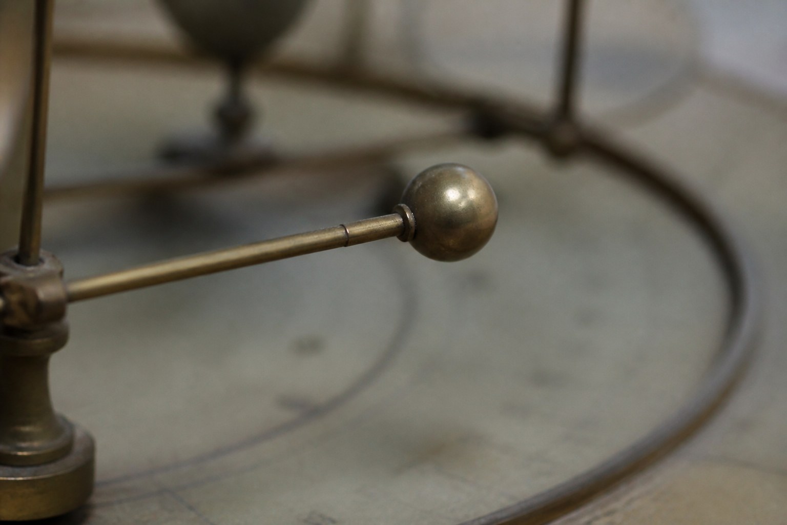 A single brass orrery arm carrying one small sphere