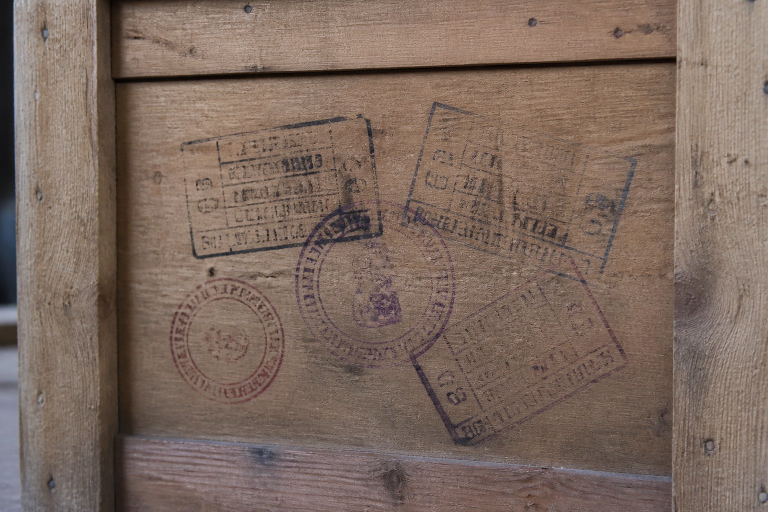 A wooden shipping crate with several overlapping customs stamps on its side