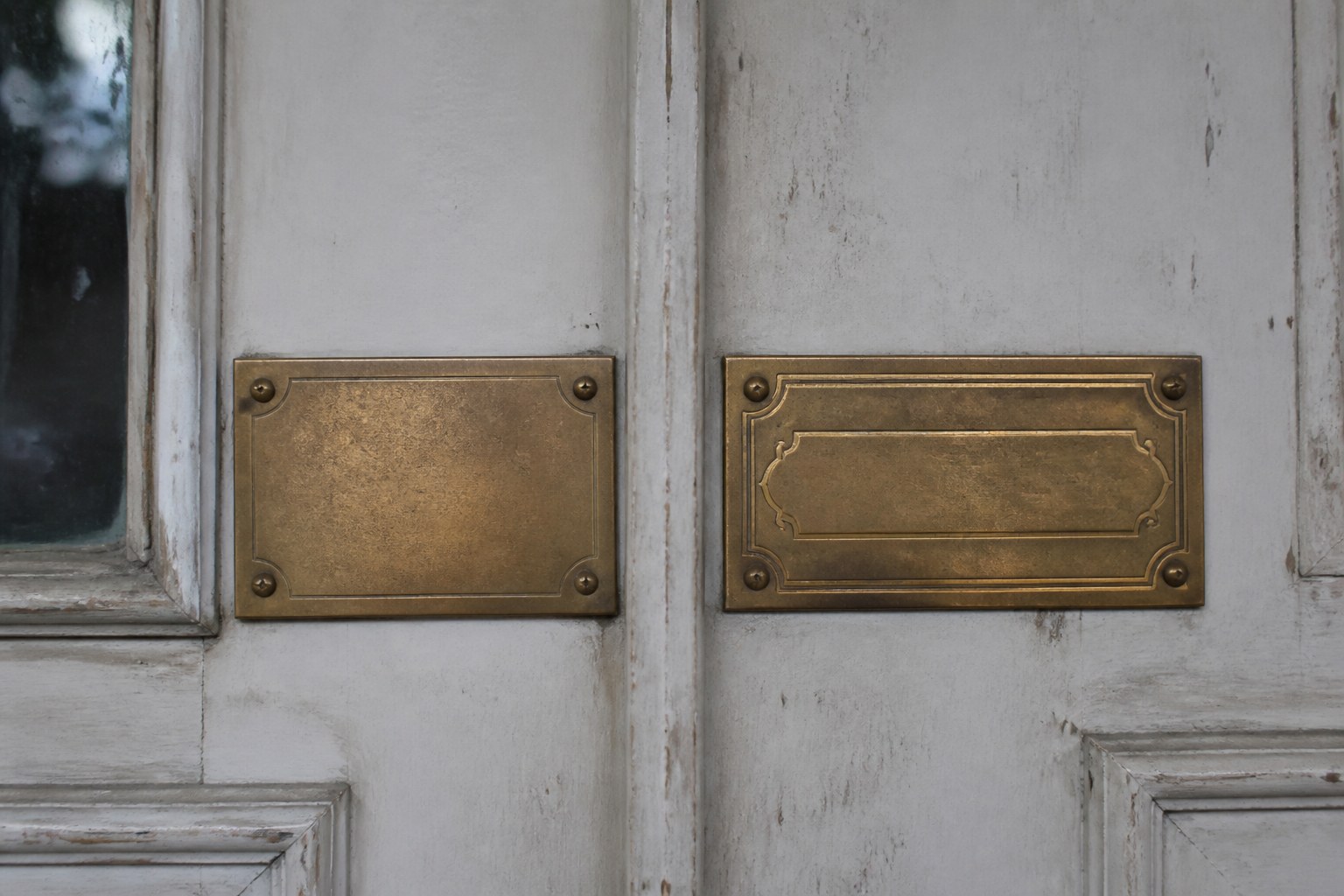 Two brass nameplates screwed side by side on a painted door