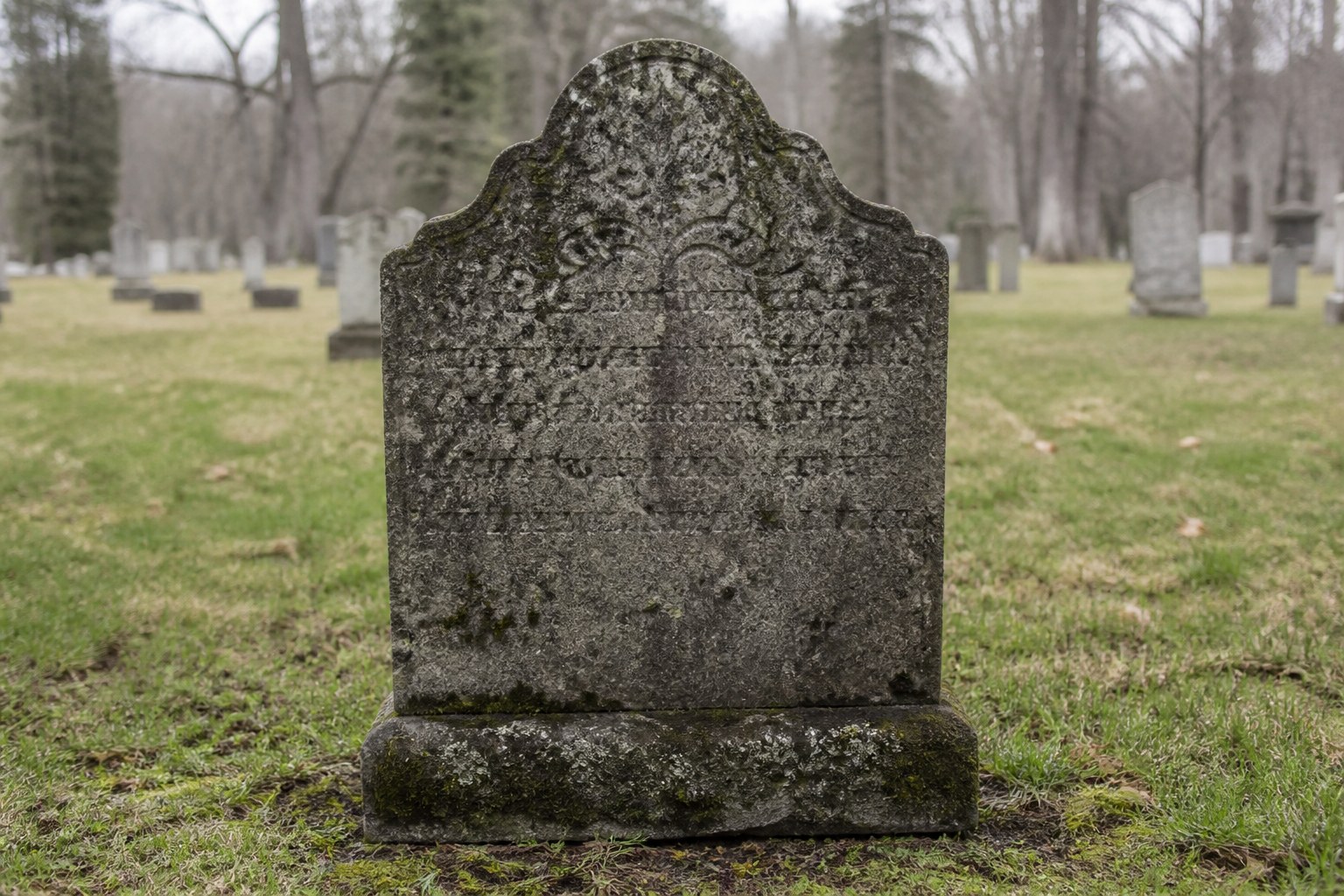 A carved family gravestone with several names weathered past reading