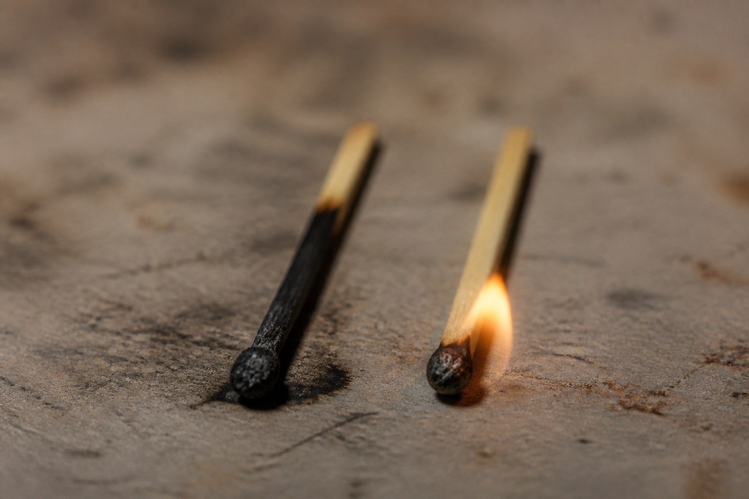 Two struck matches lying side by side, one burnt down and one barely lit