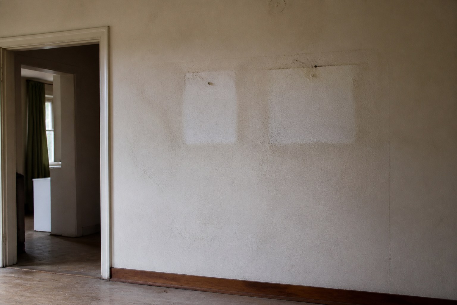 An empty room with pale rectangles on the wall where pictures used to hang