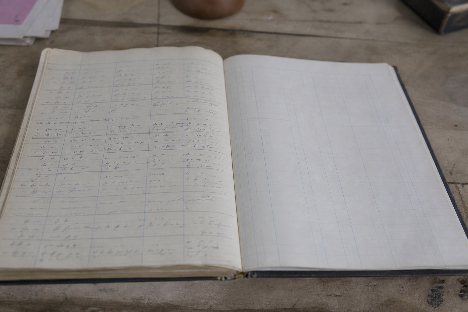 A ruled ledger opened flat with two columns, one written in and the other blank