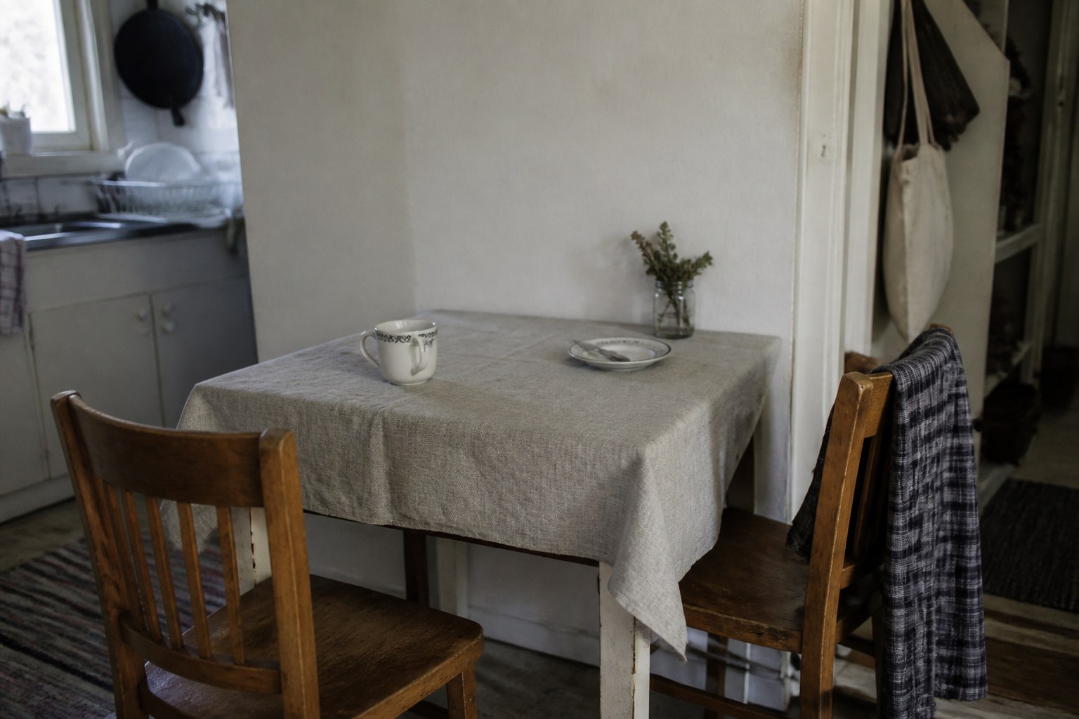 Two chairs pulled up to a small table with a cup at one place only