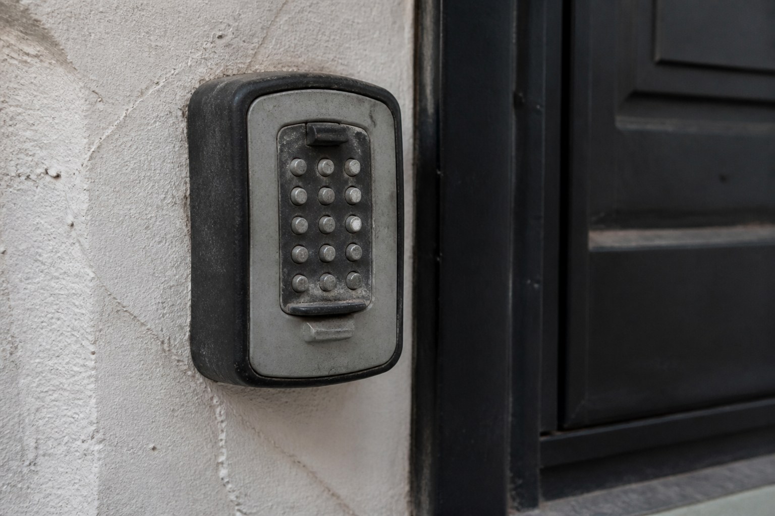 A wall-mounted key safe beside a front door with worn keypad buttons