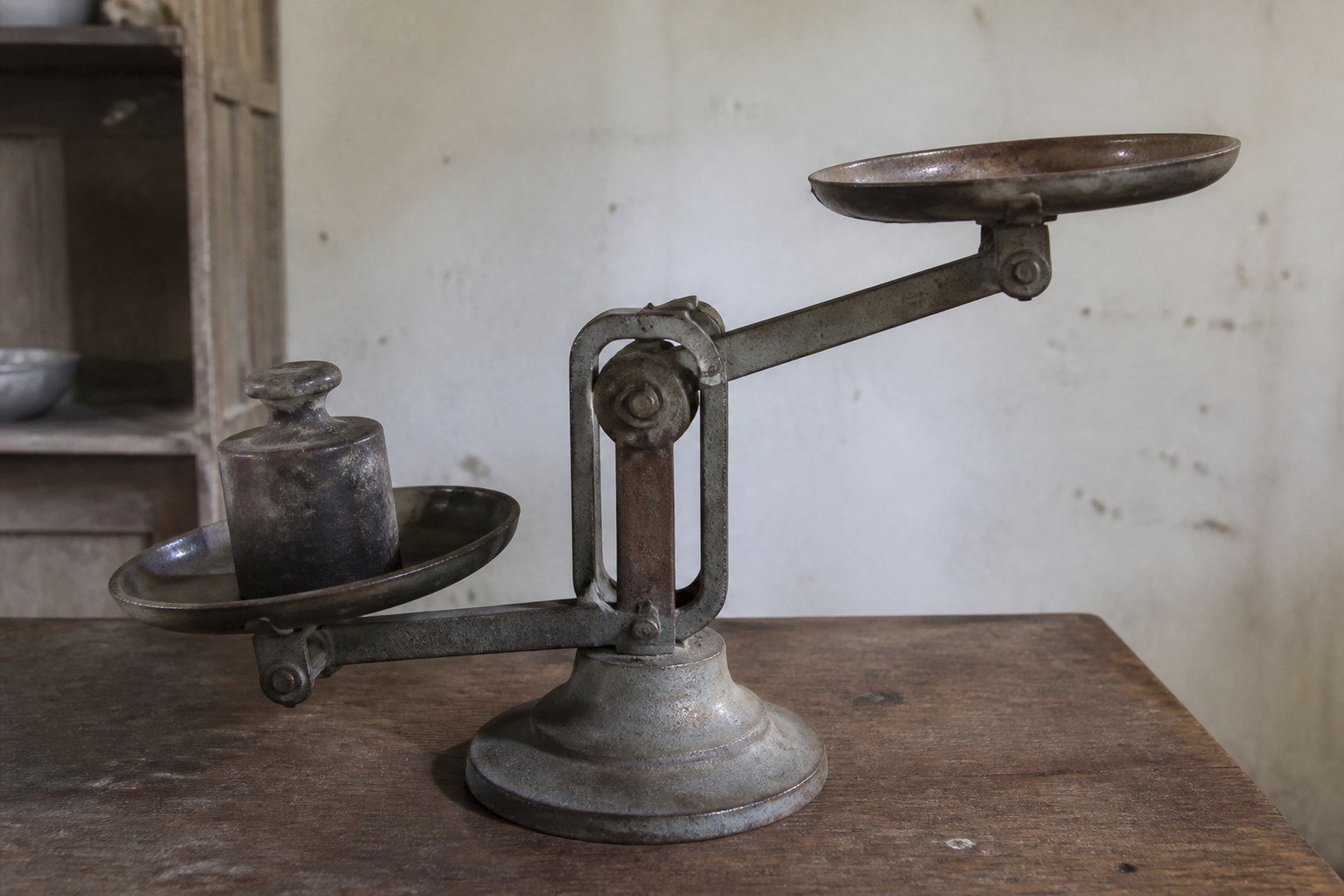 A balance scale with a heavy weight on one pan and the other empty and raised