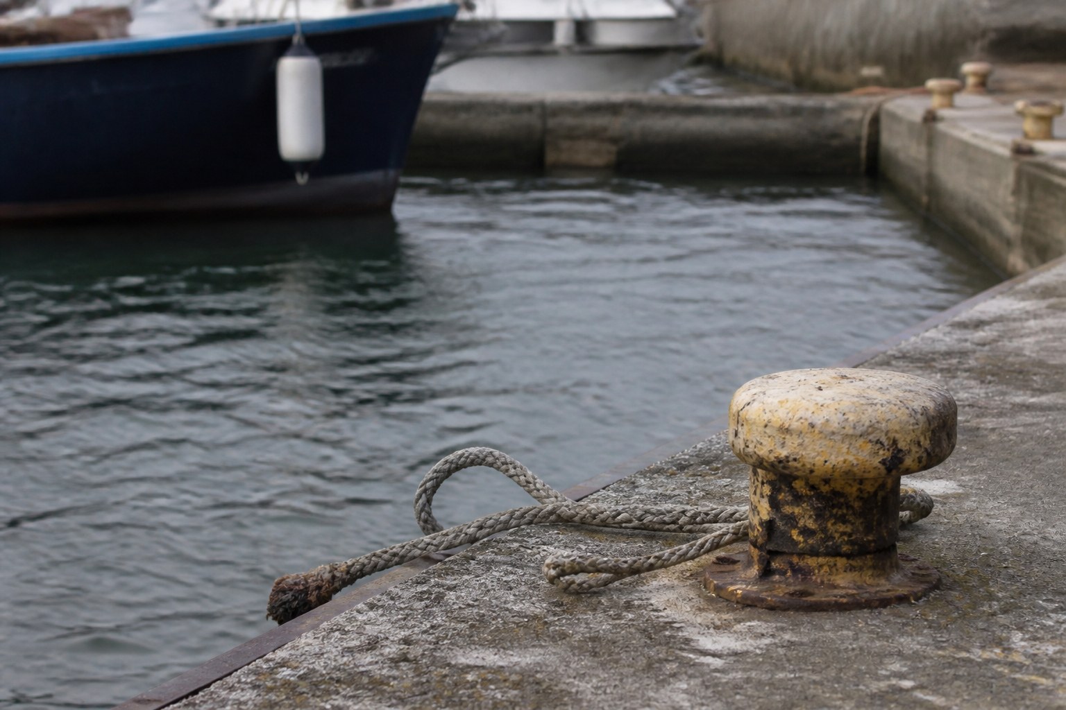 A mooring rope thrown loose from a quay bollard, the boat already a few feet off