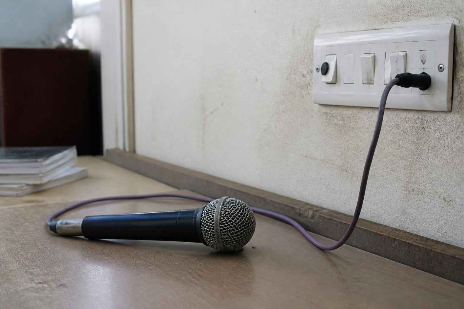 A microphone on a desk beside a mains switch, a cable running between them