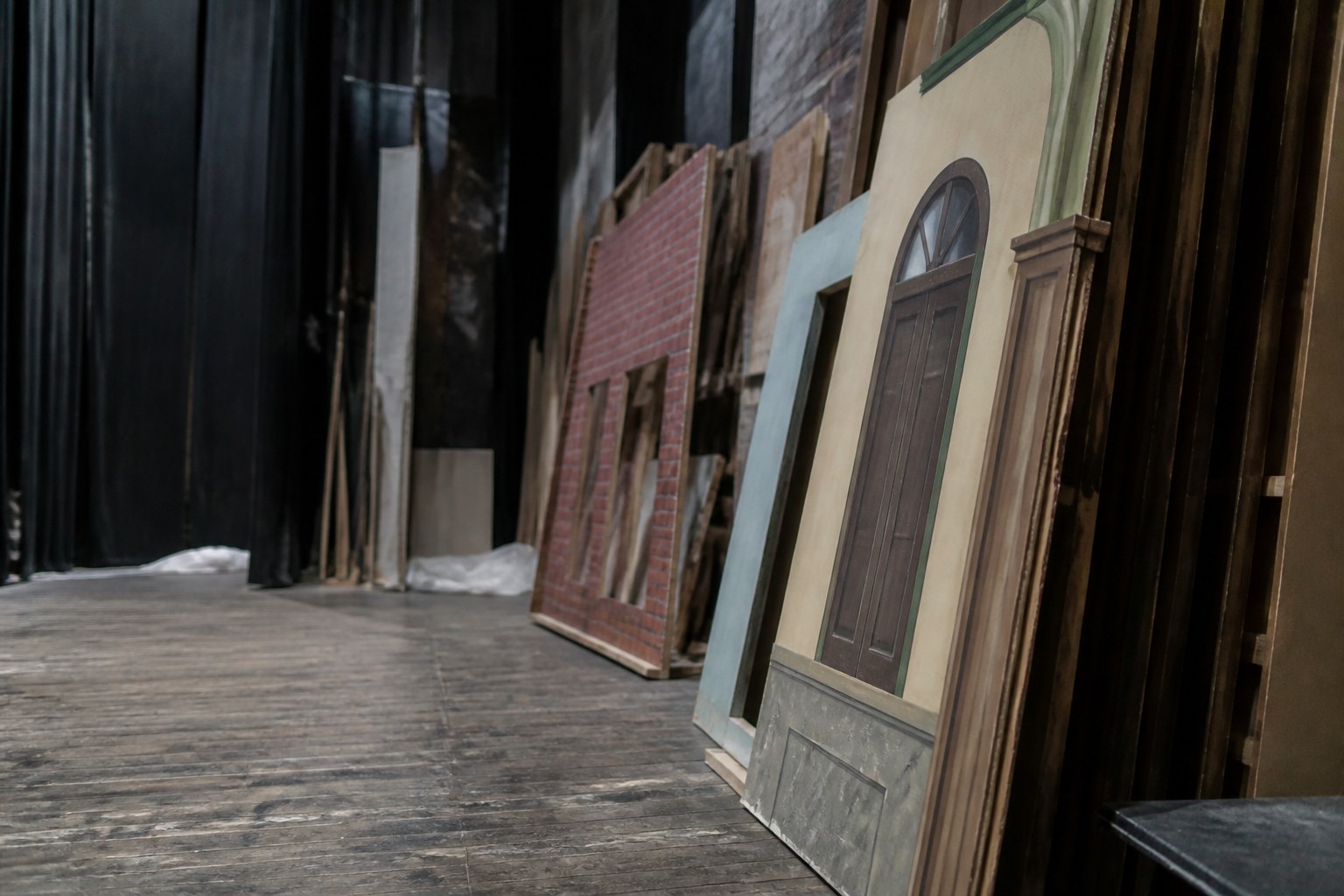 A theatre set part struck, flats stacked against a wall and the stage floor bare