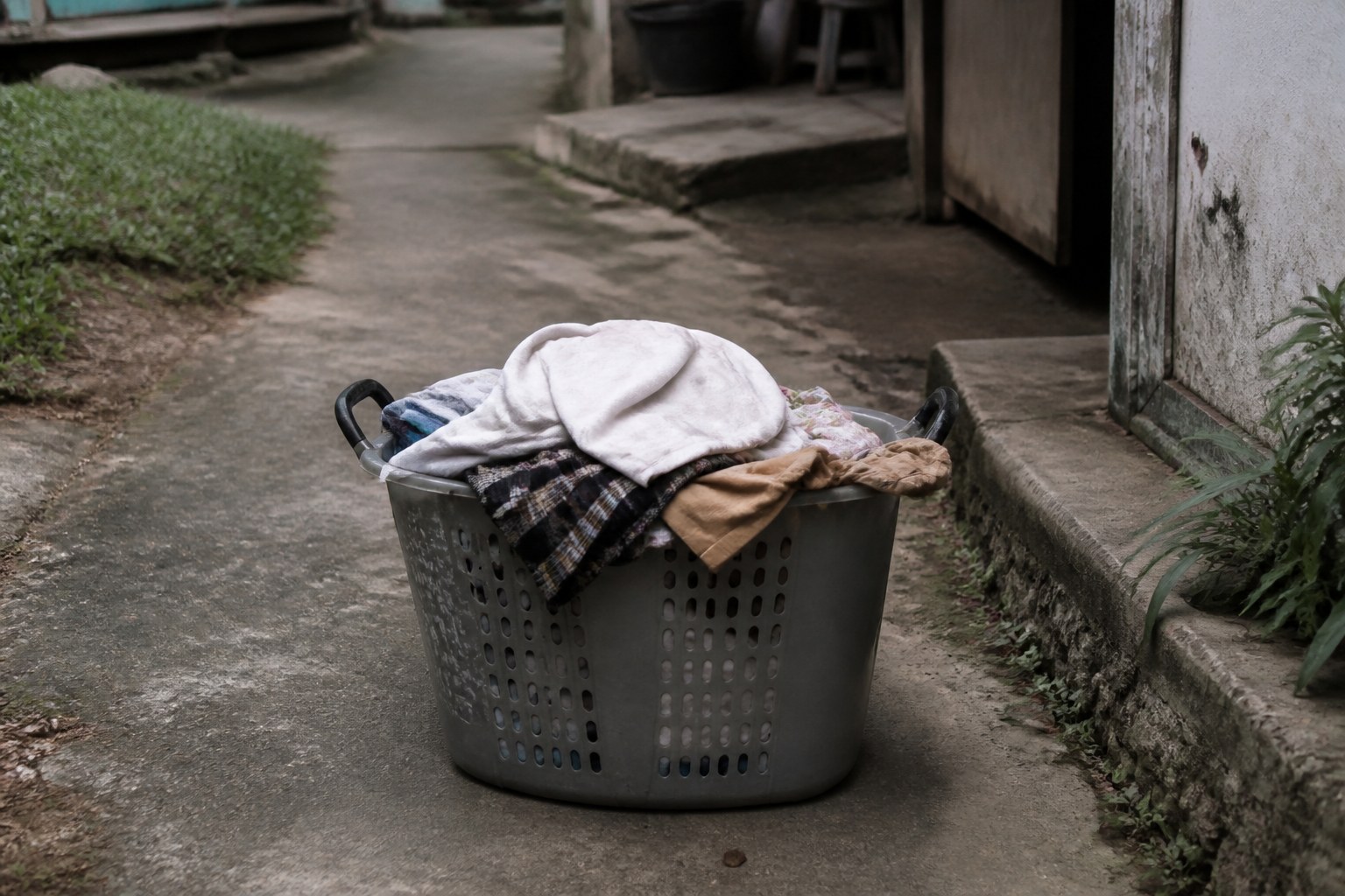 A heavy laundry basket with a handle at each end set down on a path