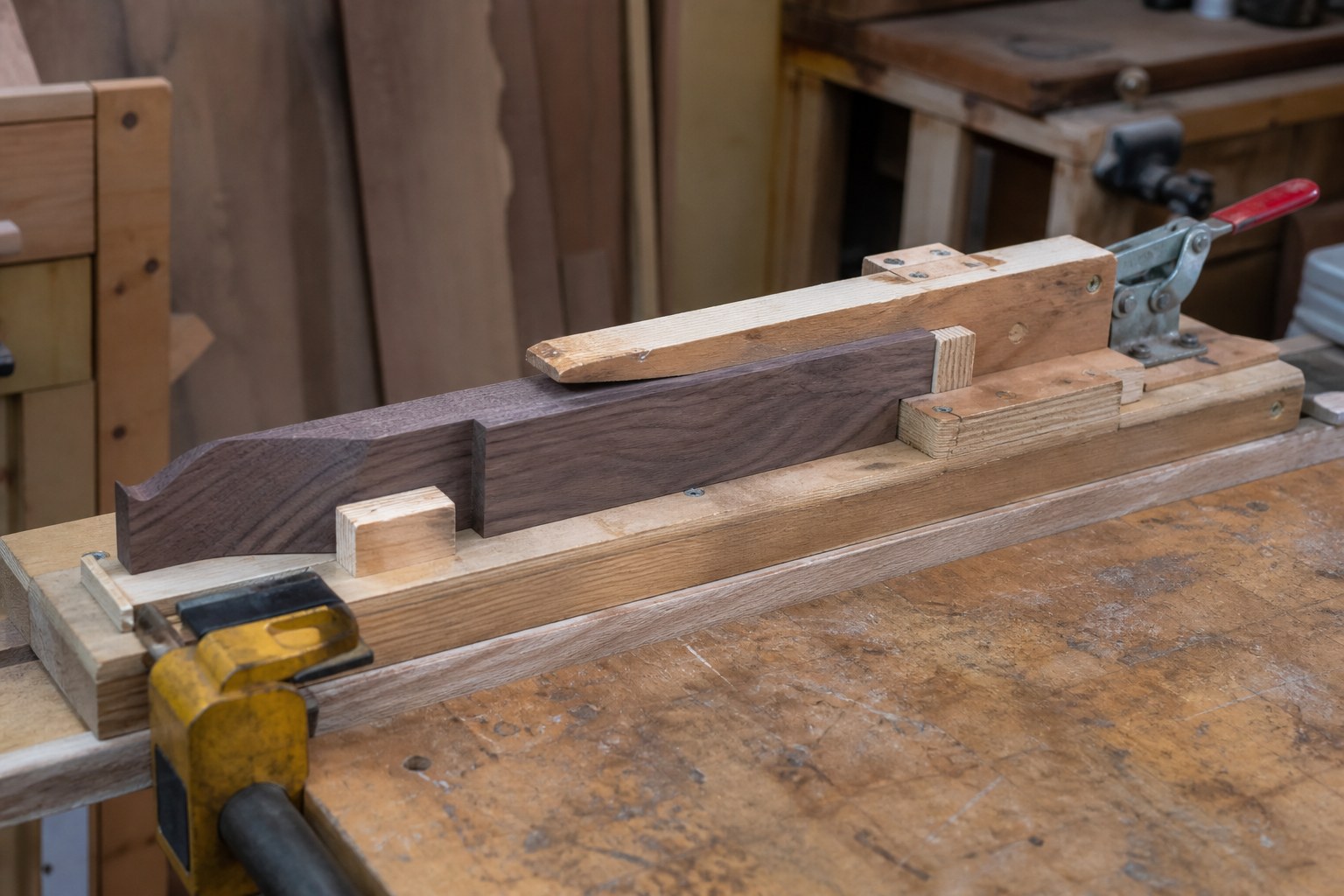 A shop-made wooden jig clamped to a bench with a workpiece held in it
