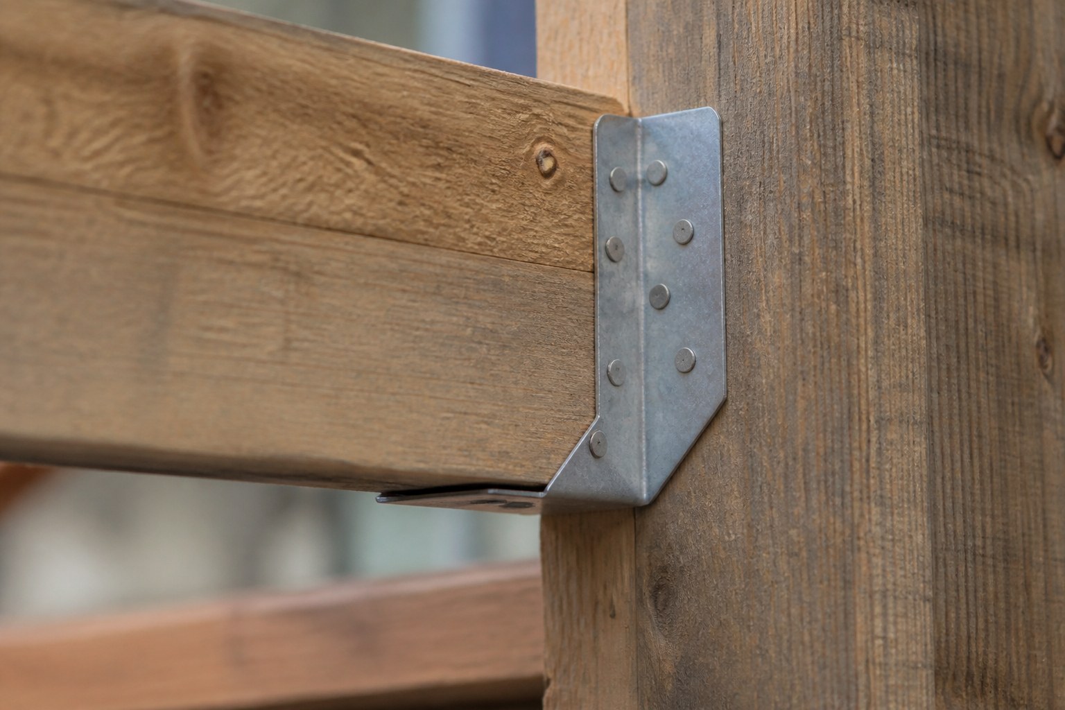 A galvanised steel joist hanger nailed into a timber beam with the fixings fully driven