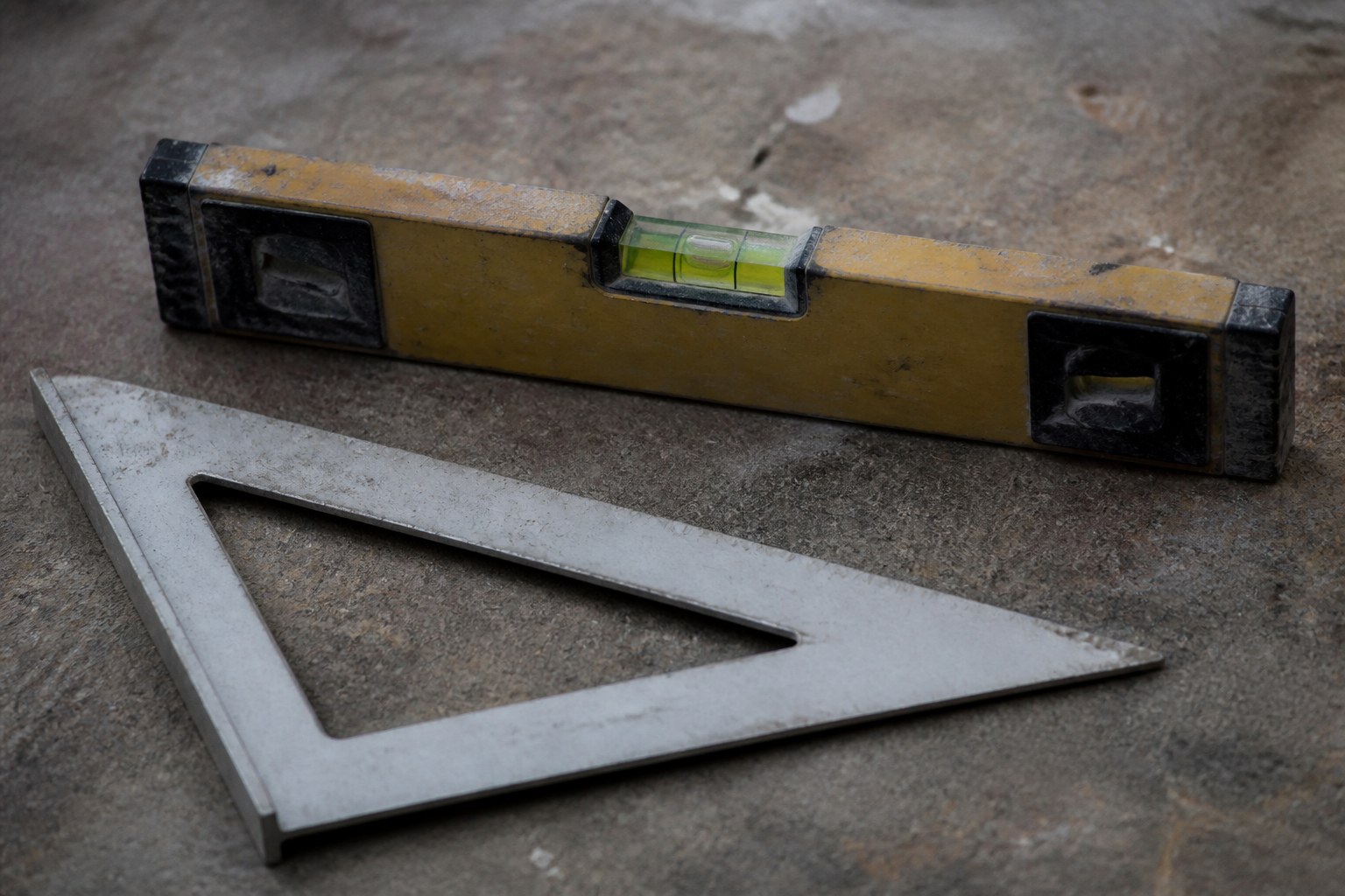 A set square lying beside a spirit level whose bubble is off centre