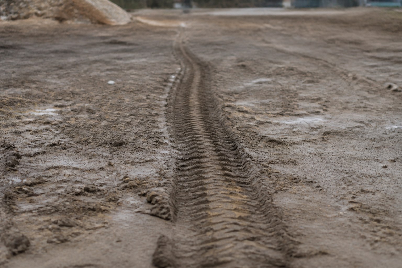 A single set of tyre tracks crossing an unmarked expanse of mud