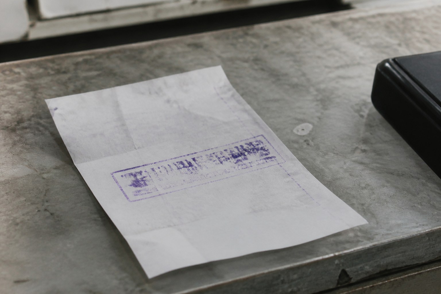 A paper receipt with a rubber stamp mark pressed across it