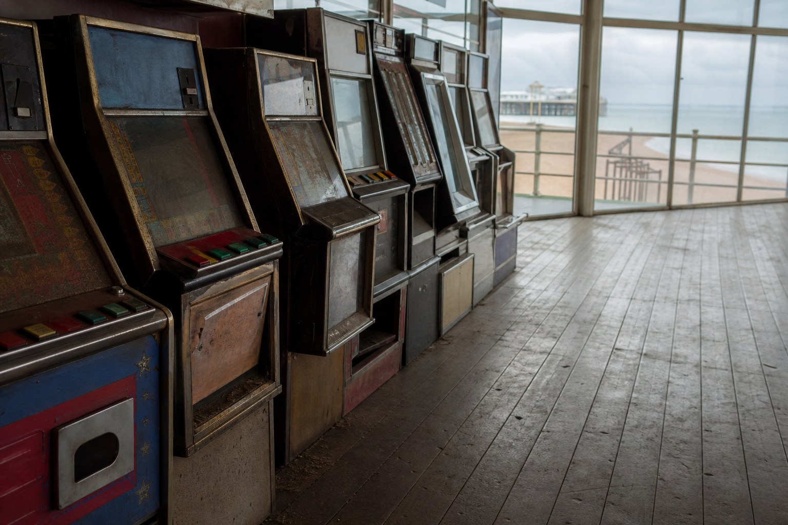 A row of old fruit machines standing unlit in an empty arcade