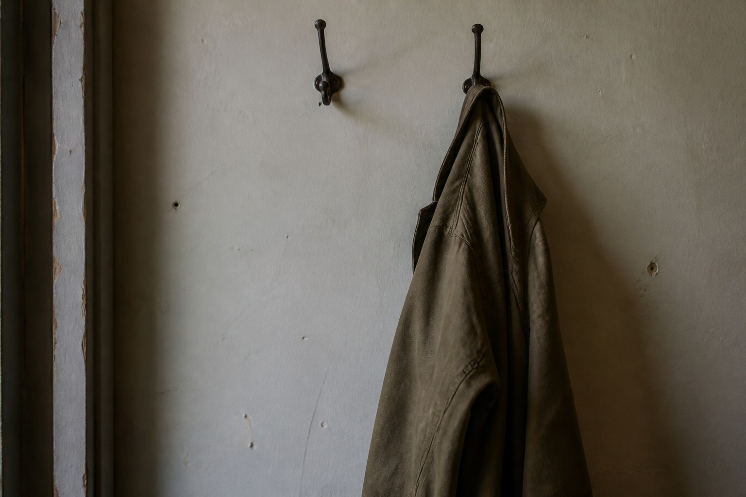 A single coat left on a hook beside an empty second hook