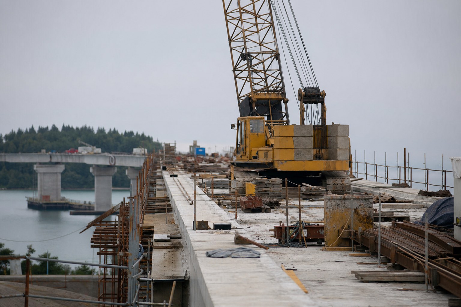 A long span bridge under construction with a temporary crane on the deck