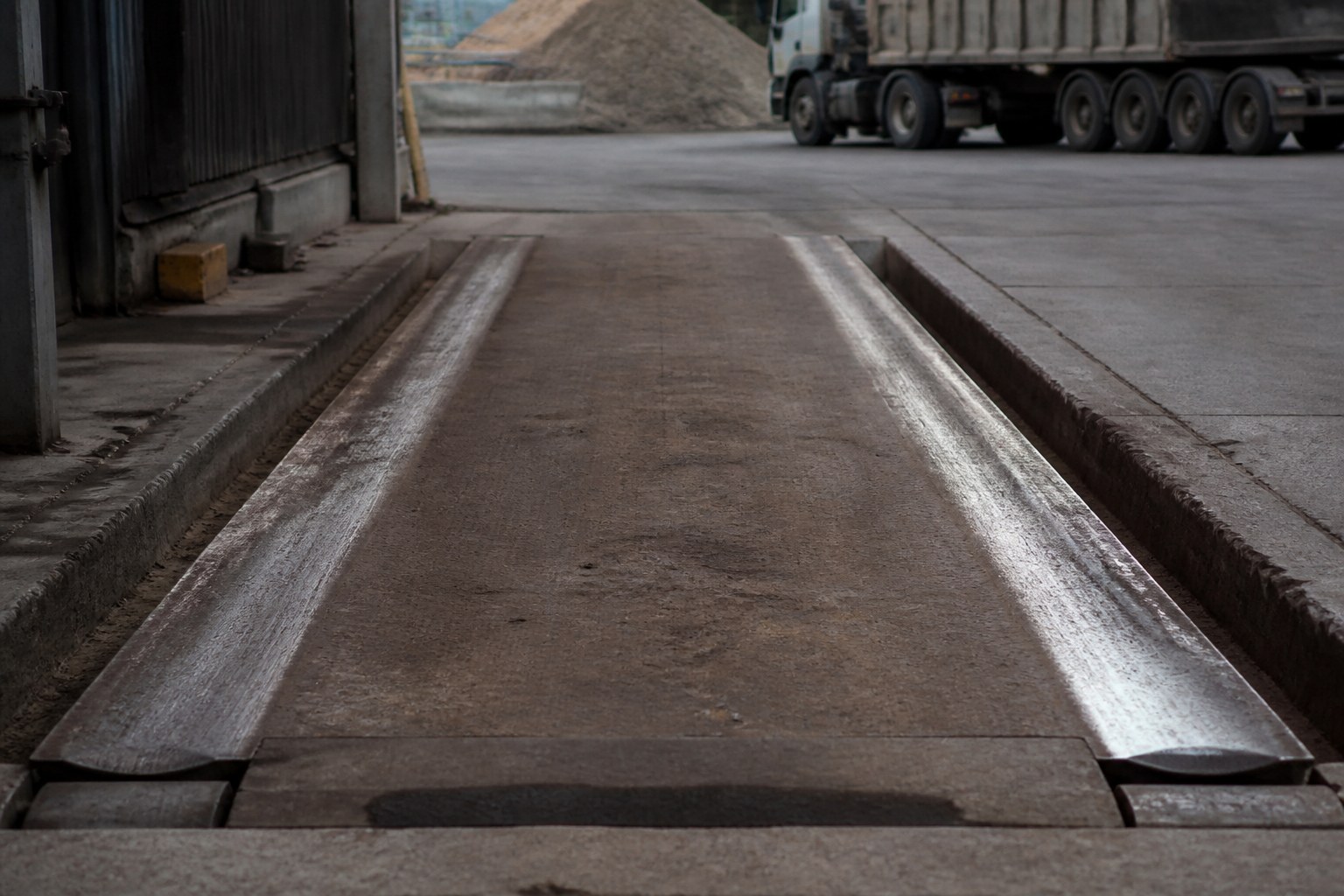 A weighbridge platform set into a yard surface with its rails worn bright