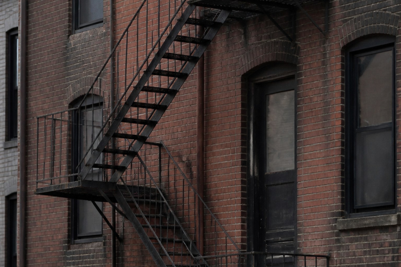 An iron fire escape staircase on the outside of a brick building