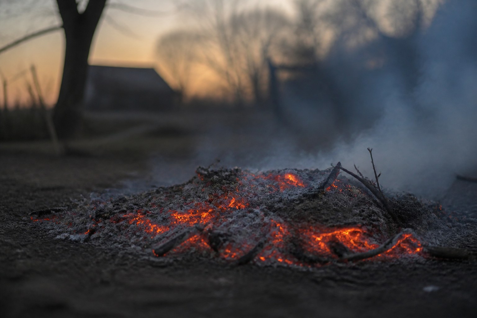 A bonfire of cleared prunings burnt down to embers at dusk