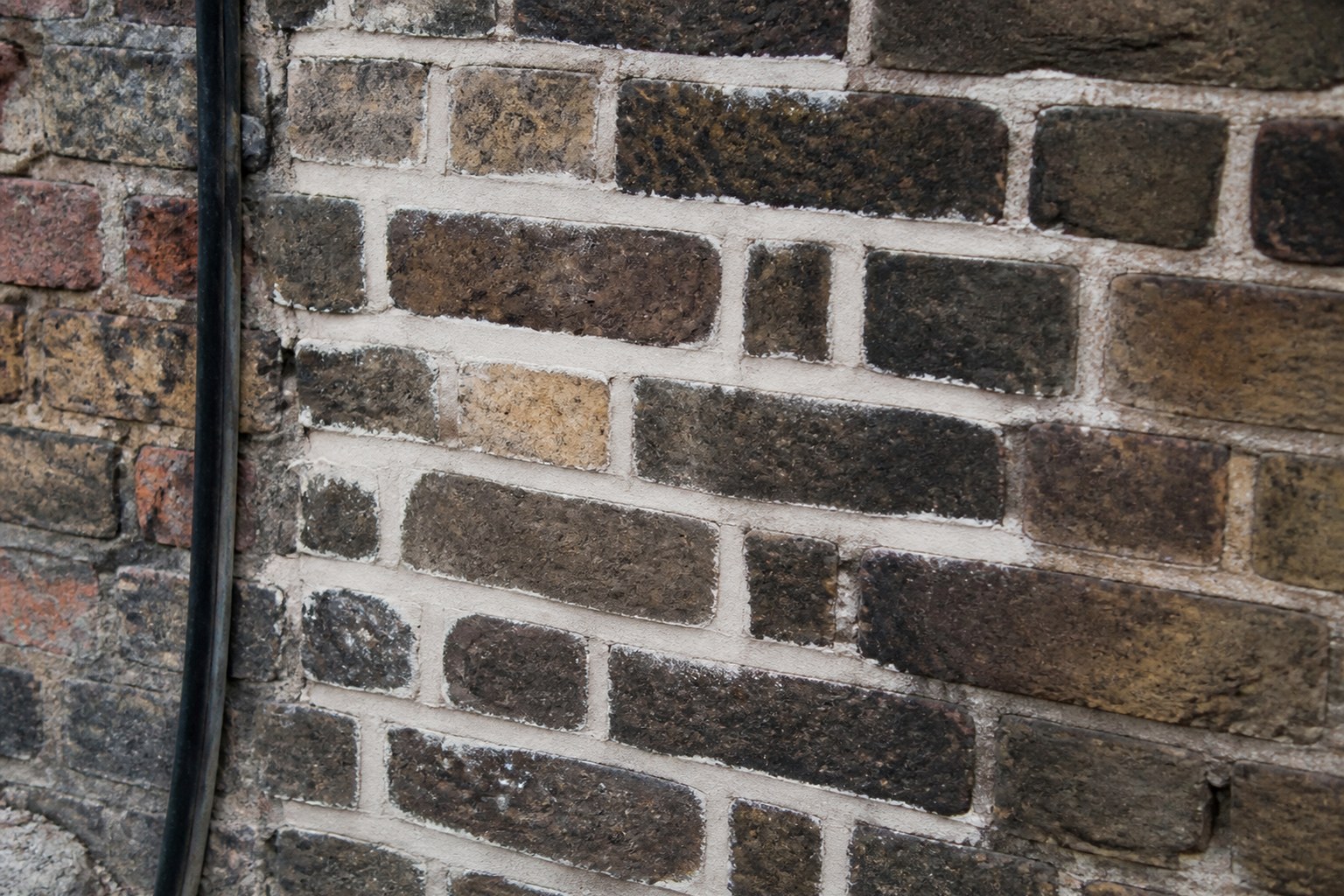 A section of old brickwork newly repointed, fresh mortar pale against weathered brick