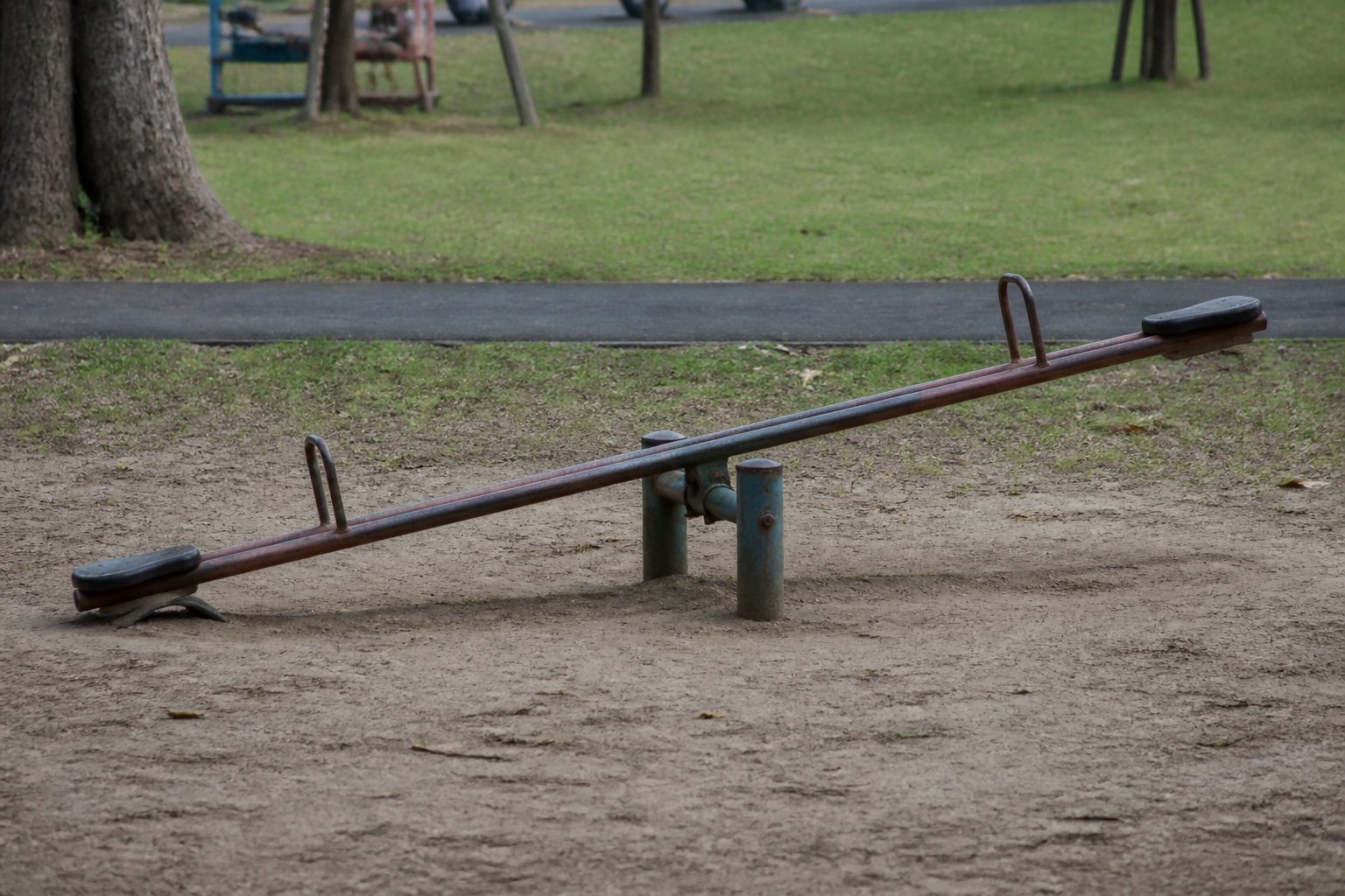 A park see-saw at rest with one end down on the ground