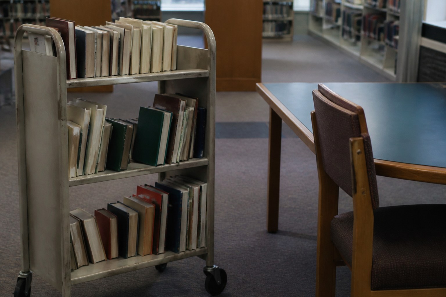 A library trolley of returned books beside an empty reading desk