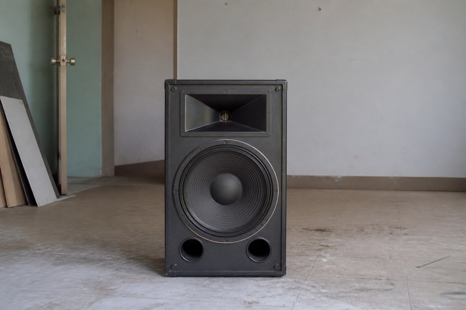A single loudspeaker cabinet facing an empty room