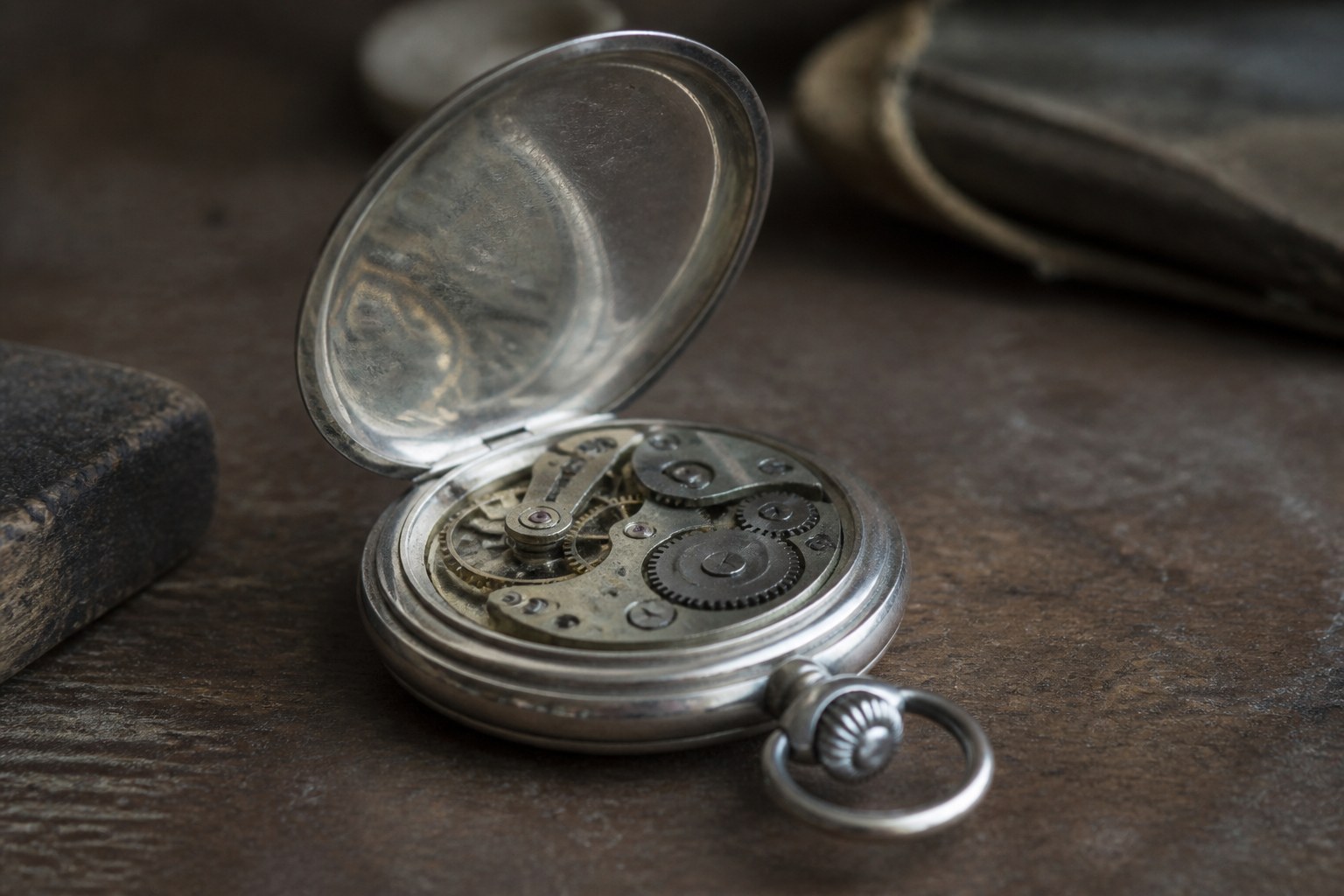 An open pocket watch case with the cover raised and the dial turned away from the camera