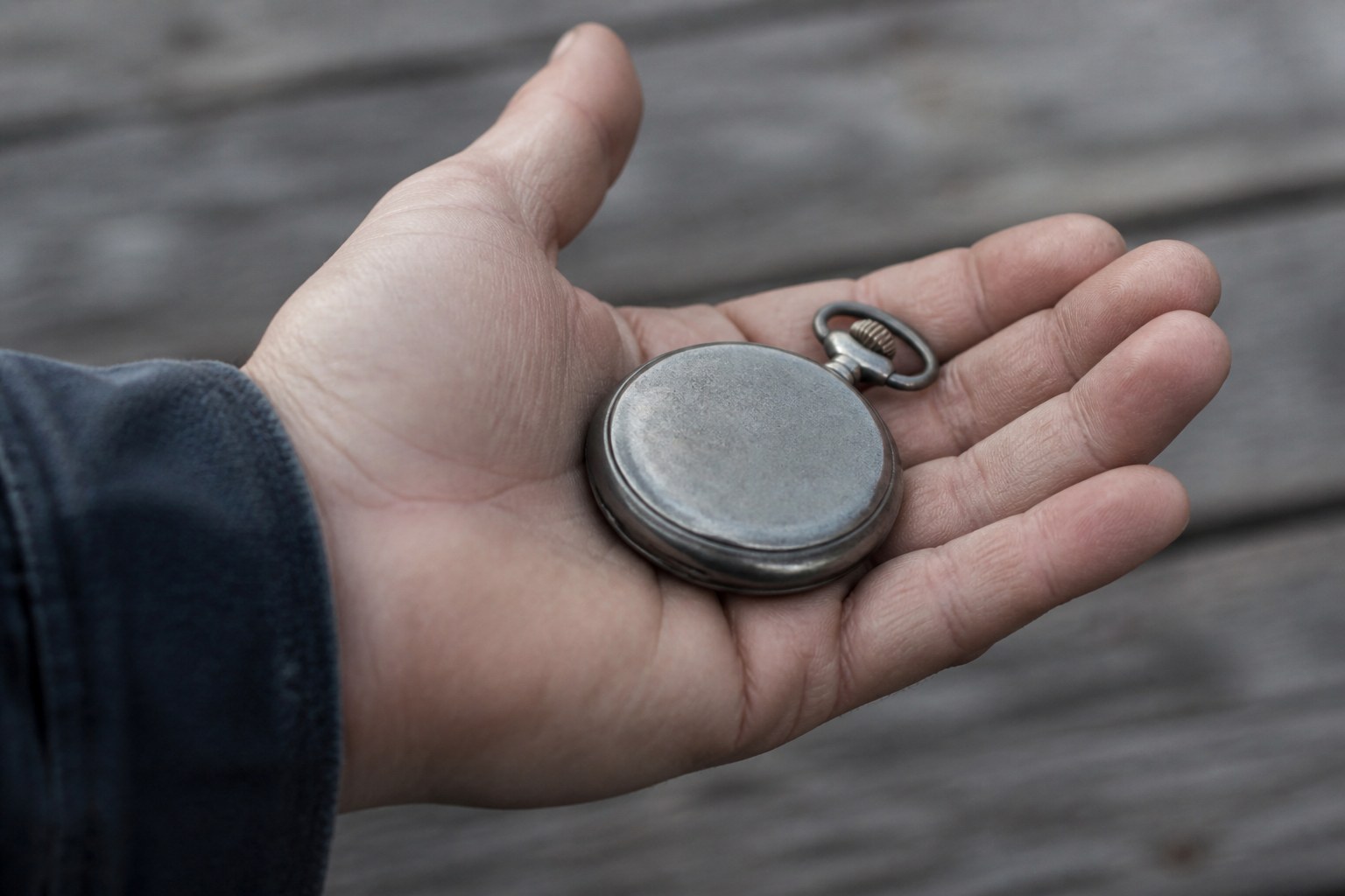 A stopwatch lying in an open palm with its dial tipped away from view