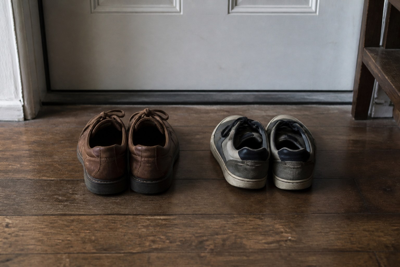 Two pairs of shoes side by side just inside a front door