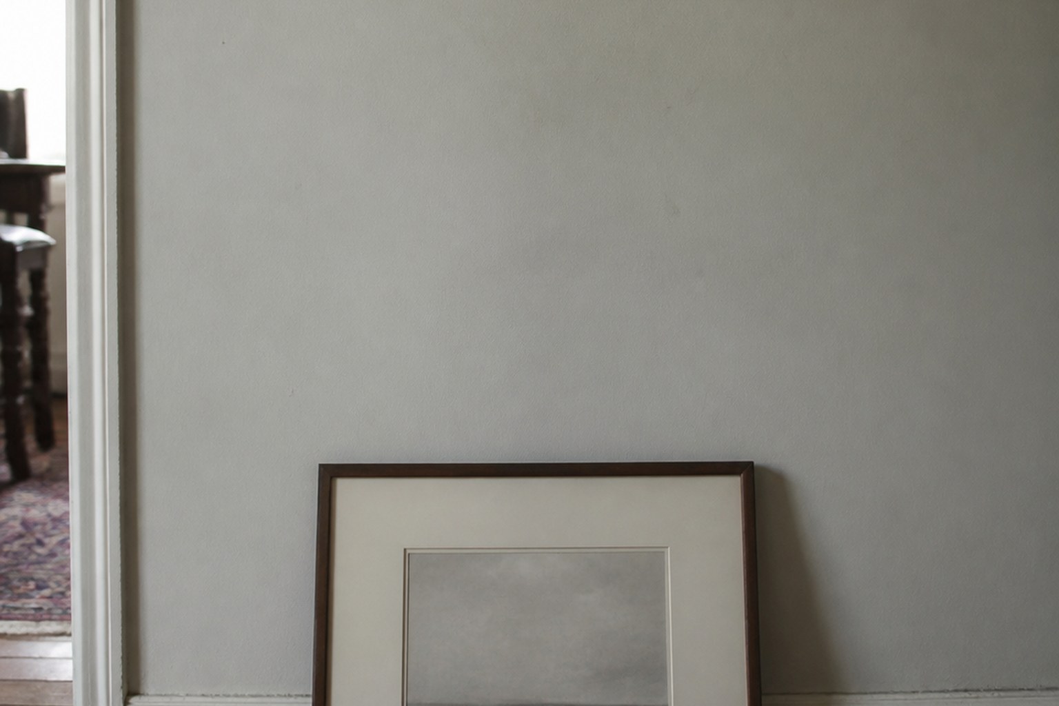 A framed picture leaning unhung against the wall below the place it should hang