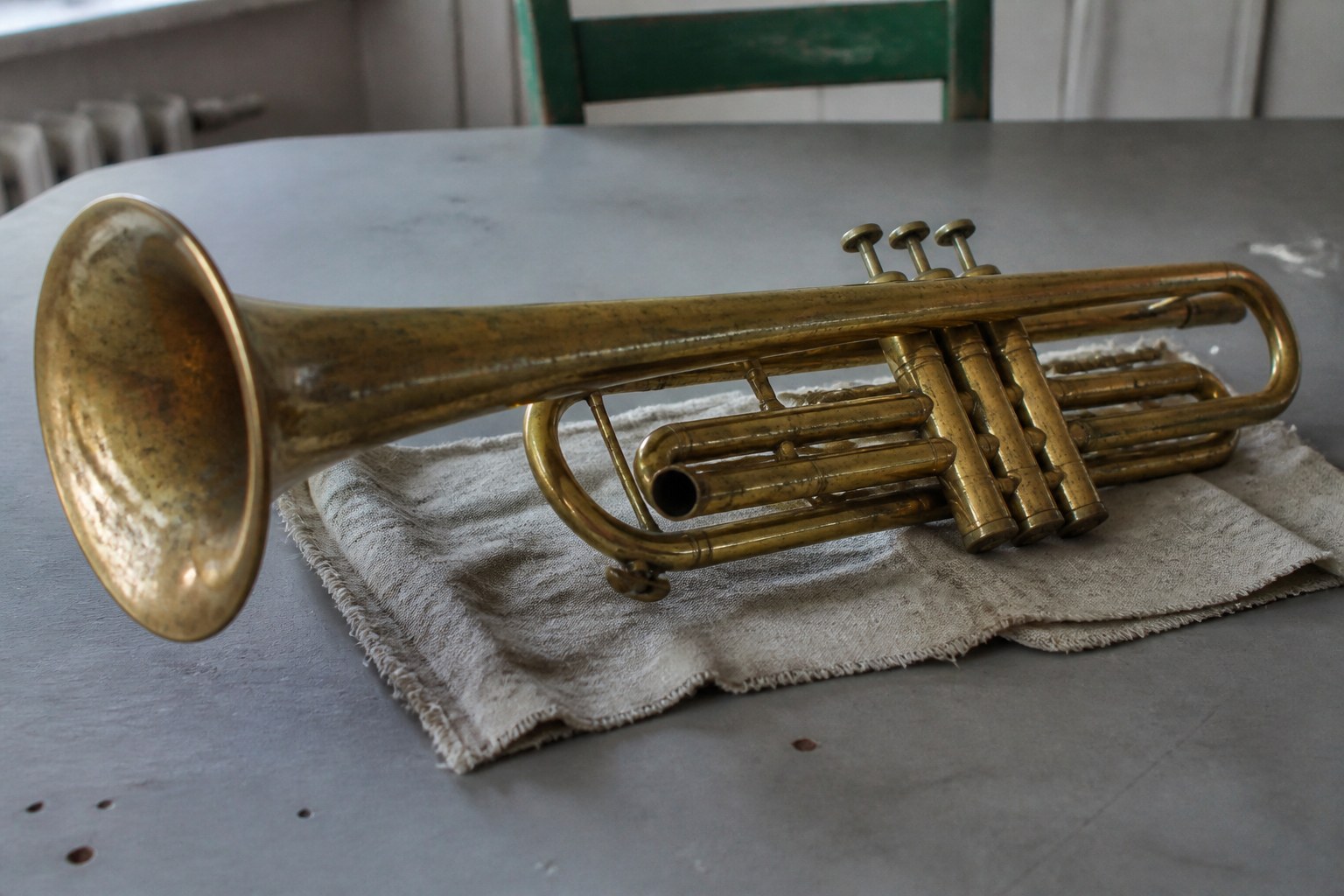 An old brass trumpet lying on a folded cloth on a plain table