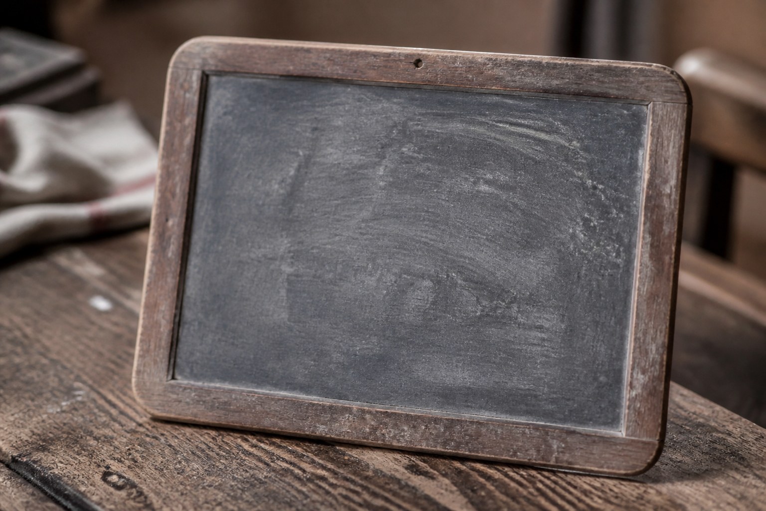 An old writing slate wiped mostly clean, with faint chalk ghosting still showing across the surface