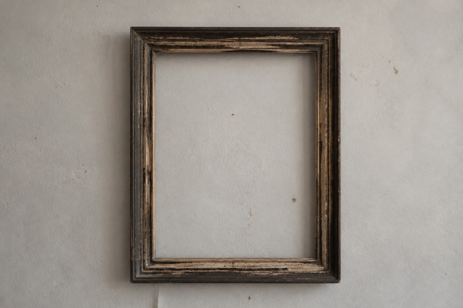 An empty picture frame hanging alone on a plain painted wall