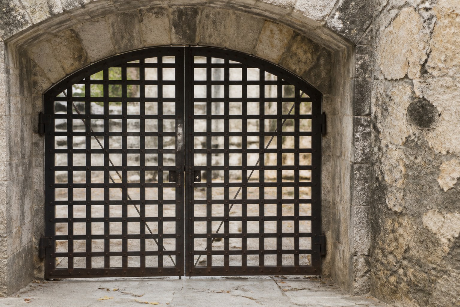 A heavy iron gate closed across a weathered stone archway