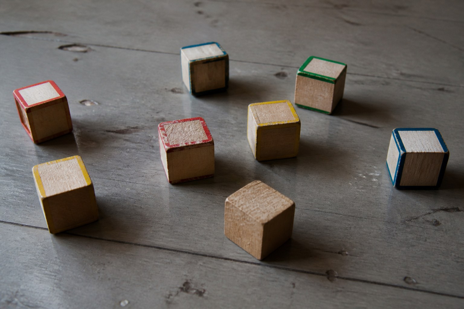 Wooden alphabet blocks on a bare floor with one turned face down