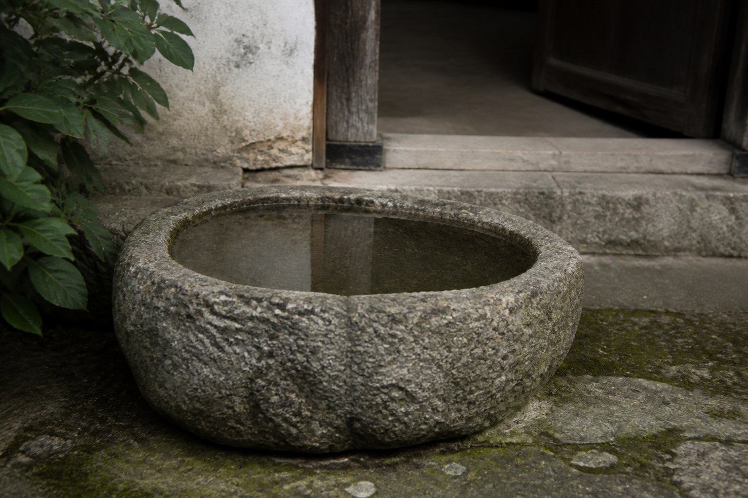 A shallow stone basin of still water beside a house doorway