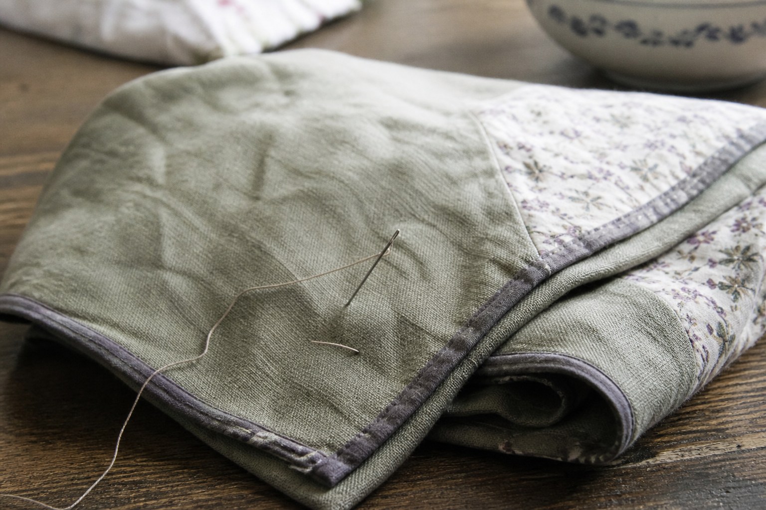 A folded piece of sewn cloth with a threaded needle still in it